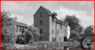 Coton Mill, a tall brick mill building beside the water.