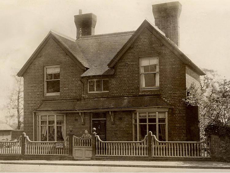 Large brick house with tall chimneys behind railings.