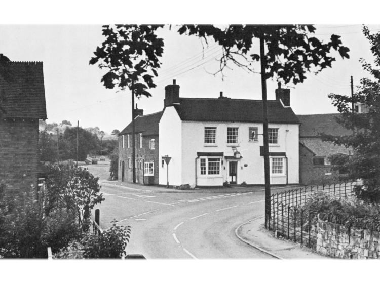 White rendered building on a bend in the road, with railings.