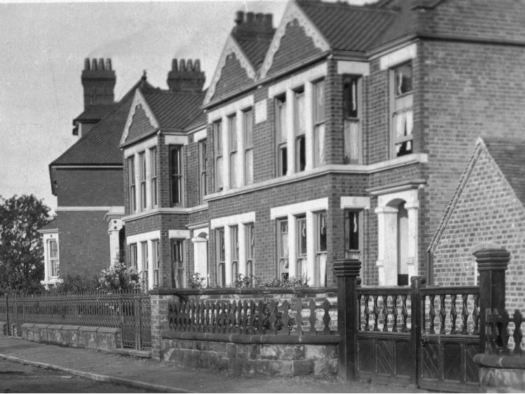 A terrace of tall gabled villas behind railings.