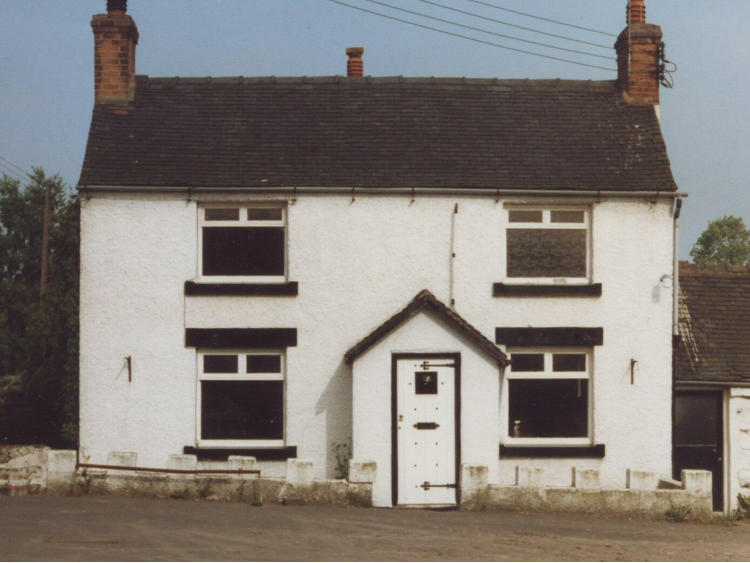 White rendered cottage with dark window surrounds.