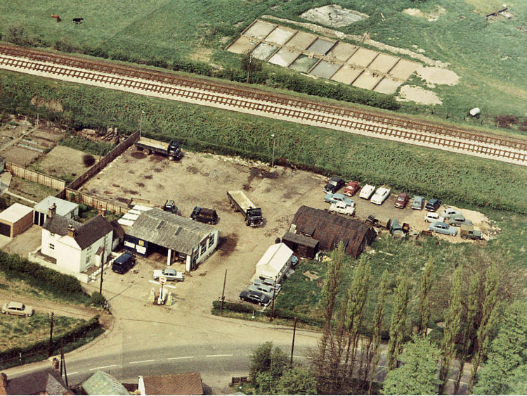 Aerial view of a yard with vehicles and glasshouses.
