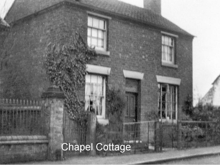 Chapel Cottage: a brick cottage with creeper and railings.