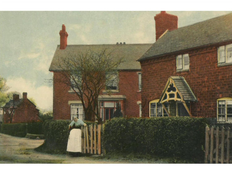 Hand-coloured view of a brick house with a swing in the garden.
