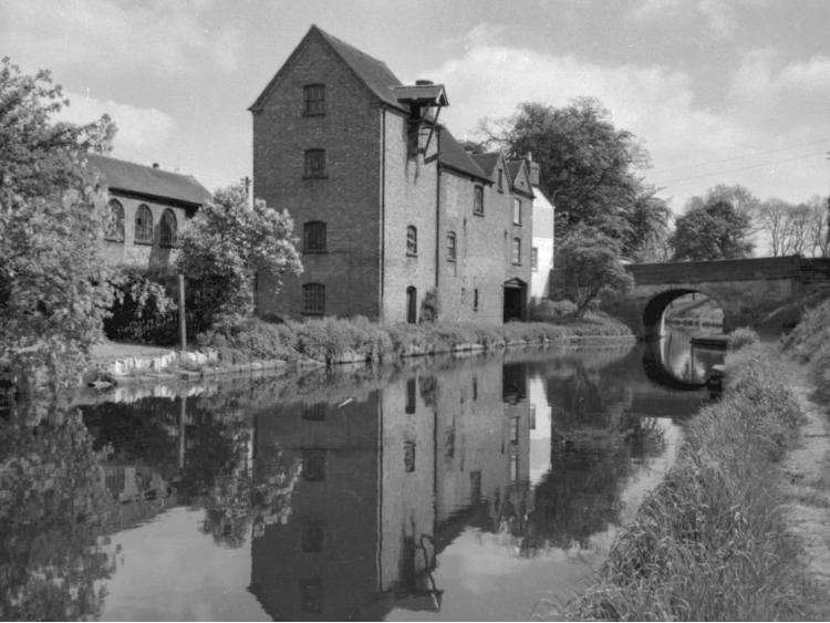 The mill reflected in the canal, with the bridge alongside.