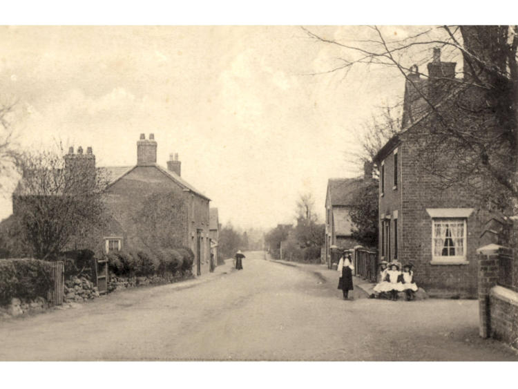 Figures outside a cottage on the road.