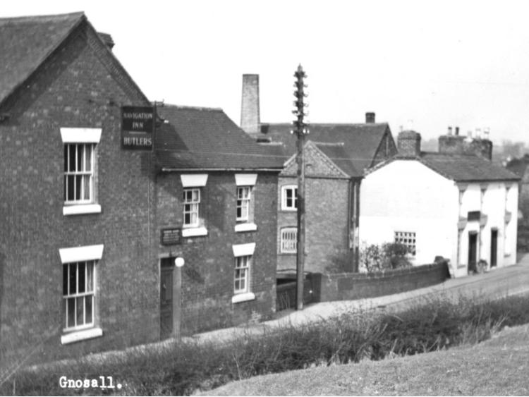 Postcard captioned &ldquo;Gnosall&rdquo;, buildings on rising ground.